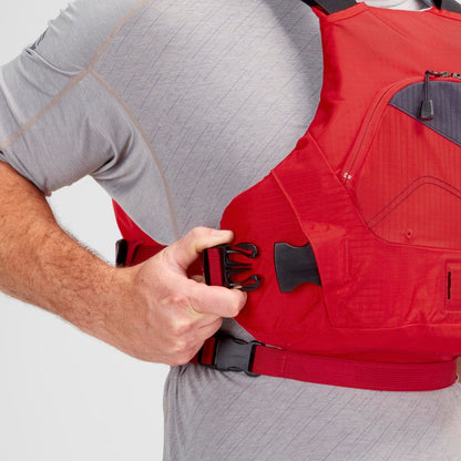 A person in a gray shirt adjusts the strap of an NRS Ion PFD, boasting black buckles and ultra-soft foam for added comfort.