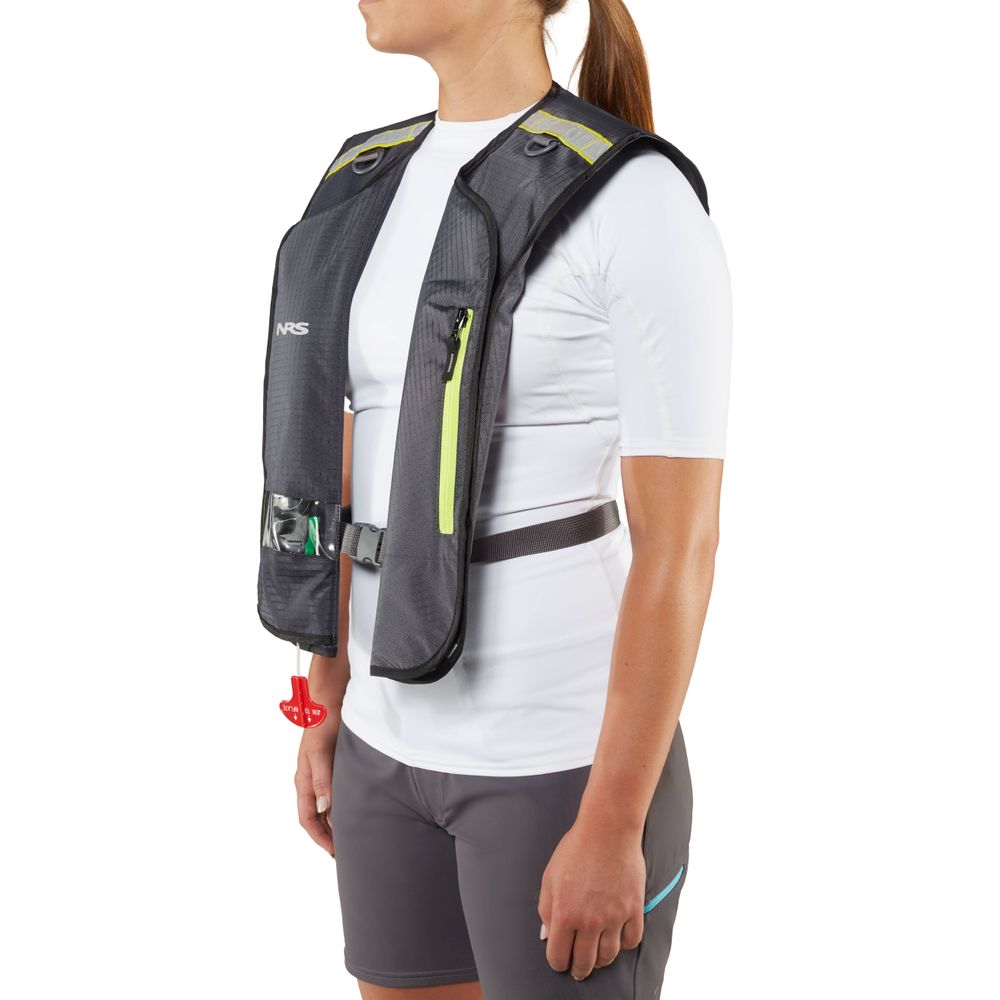 A person is wearing an NRS Matik Inflatable PFD in dark gray with neon accents over a white shirt and gray shorts, viewed from the side.