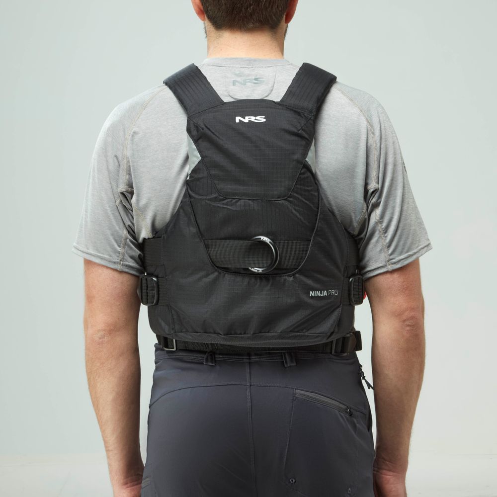 A person in a gray shirt and dark pants is seen from behind, wearing the NRS Ninja Pro PFD, a trusted rescue vest favored by whitewater paddlers.