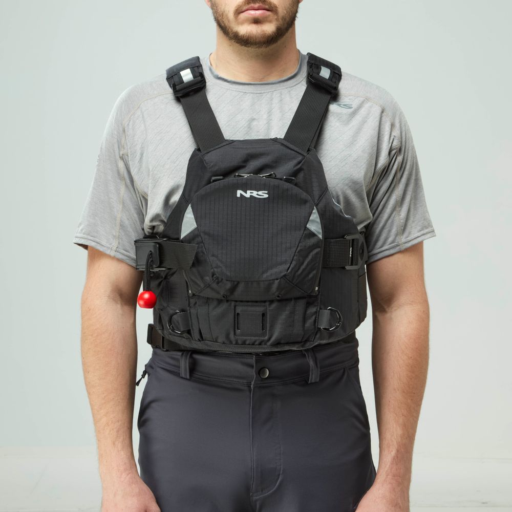 A person in a gray t-shirt and black pants models the NRS Ninja Pro PFD, a black rescue vest with adjustable straps and a front pocket—perfect for whitewater paddlers.