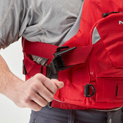 Wearing a gray shirt, someone tightens the side strap of the red NRS Ninja Pro PFD—ideal rescue gear for whitewater paddlers.