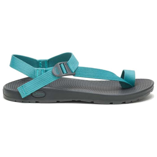 The Chaco Women's Bodhi Sandle, shown in teal and gray with adjustable straps and a textured sole, offers lightweight everyday comfort—pictured in side profile against a white background.