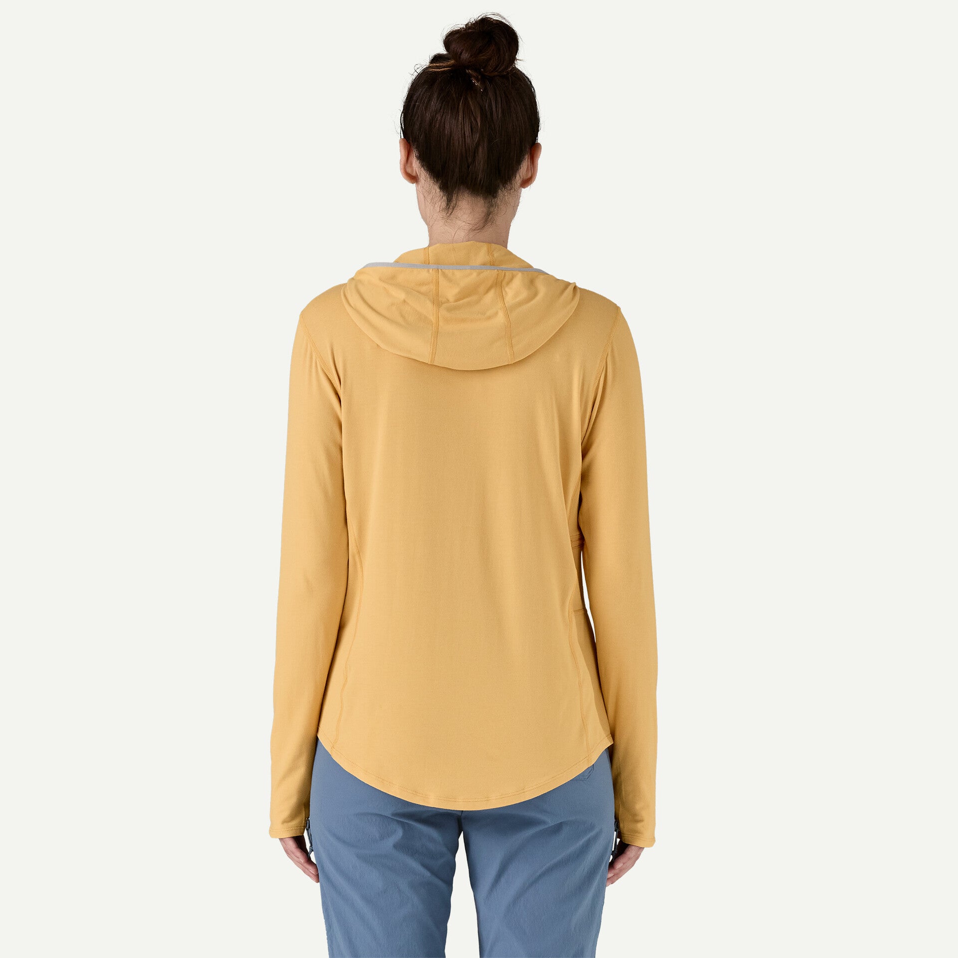 A person is wearing a Patagonia Tropic Comfort Natural Hoody W's, appearing in yellow, paired with blue pants, facing away against a light background.