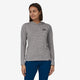 A woman stands against a neutral background, wearing Patagonia's Cap Cool Daily Graphic Hoody, crafted from recycled polyester with a small logo, paired with blue pants.