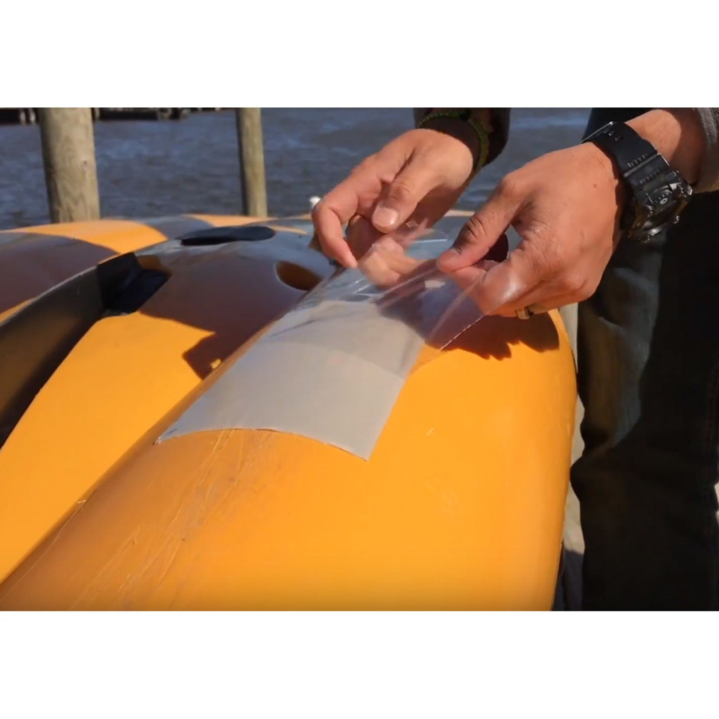 A person is repairing a yellow kayak with NRS Gator Guard Patch to ensure a watertight seal.
