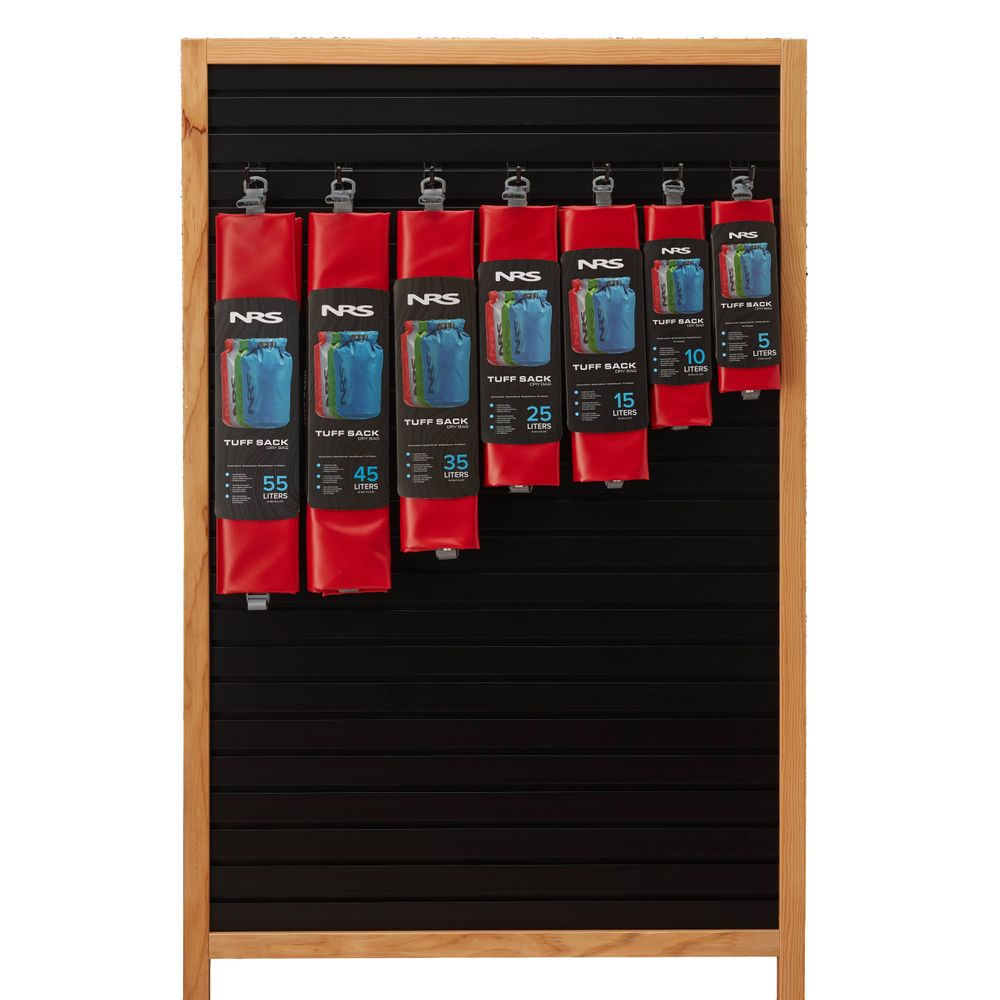 NRS Tuff Sack dry bags, equipped with the StormStrip system, are showcased in multiple sizes and a vibrant red hue, hanging on a wooden slotted board.