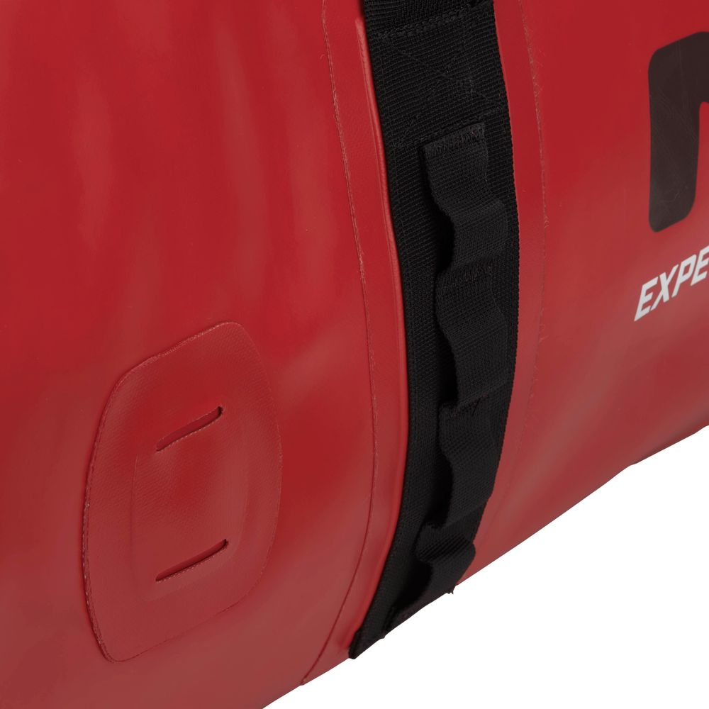 Close-up of a red Expedition DriDuffel by NRS featuring a black side strap, crafted from PVC-free material, with visible stitching and two horizontal slits on the left.