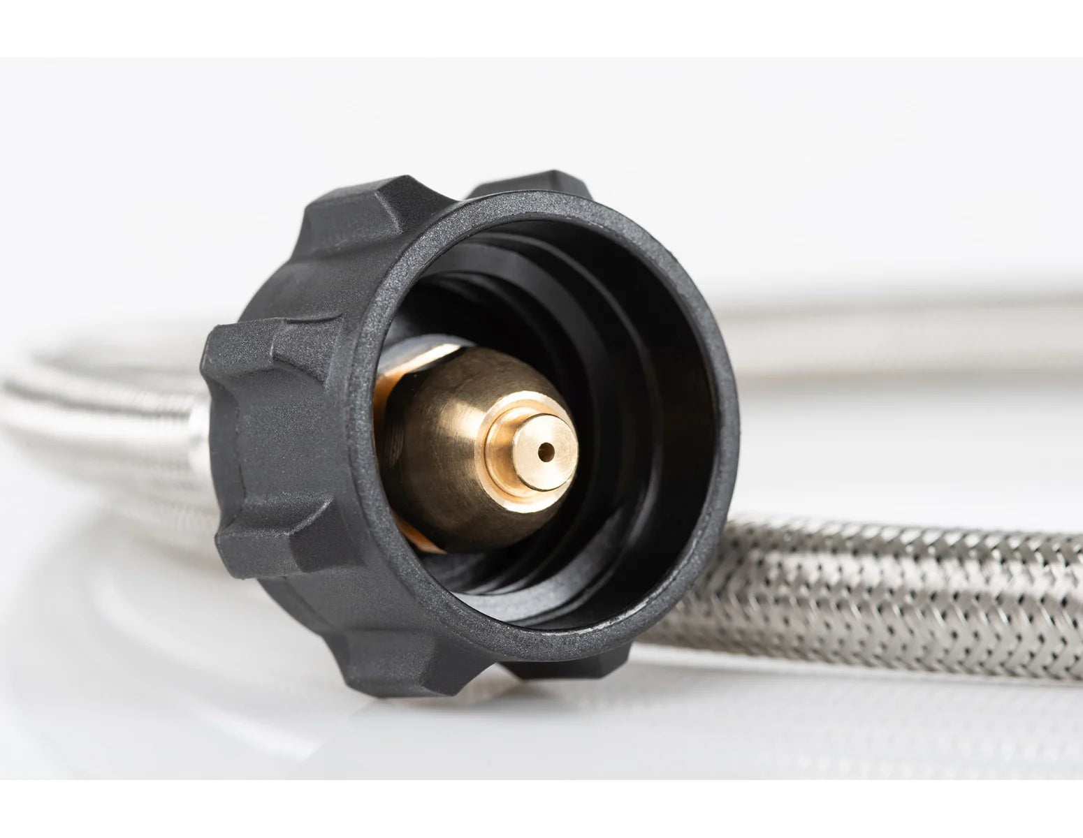 Close-up of GSI Outdoors Propane Adapter Hose with braided stainless steel, a black plastic fitting, and a brass nozzle, ideal for connecting to your camp stove.