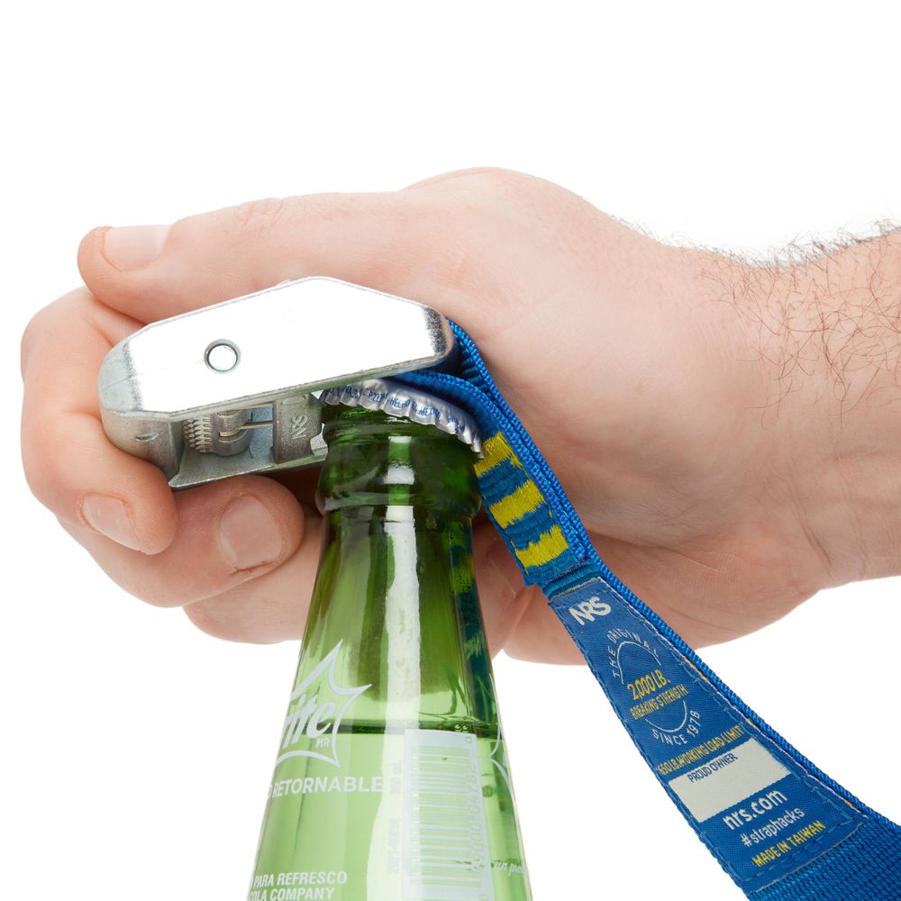 An expert hand uses the NRS Heavy Duty 1.5in Wide Cam Strap's silver and blue buckle bottle opener to easily uncap a green glass bottle.