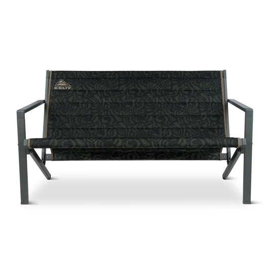 The Kelty Rad Loveseat is a portable camp loveseat featuring green and black camouflage fabric, a sturdy metal frame, armrests, and the Kelty logo on the upper left corner of the backrest.