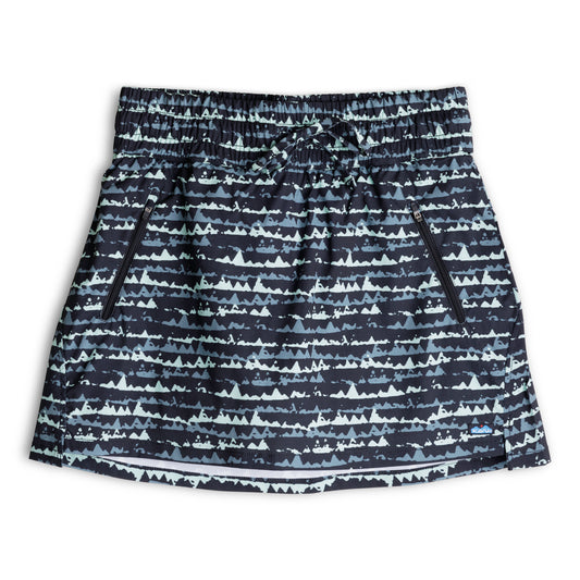 The Kavu Just Beachy Skirt is a black and white patterned skort made from recycled polyester, featuring an elastic waistband, drawstring, and two zippered side pockets, shown on a white background.