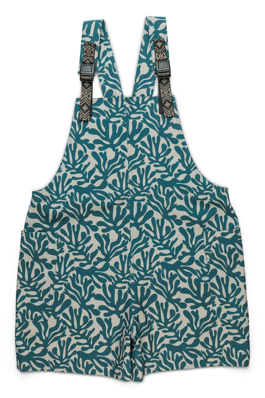 The Kavu Montanita Jumper by Kavu features adjustable straps, a blue and white coral print, two front pockets, and quick-dry fabric—ideal as a summer romper for sunny days.