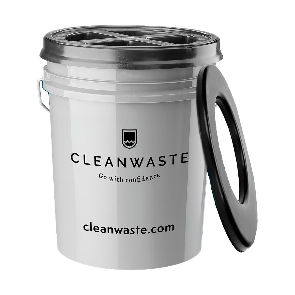 A white plastic Restop Commode portable toilet by NRS, perfect for backcountry use, features a black seat lid leaning against it and the brand's website printed underneath.