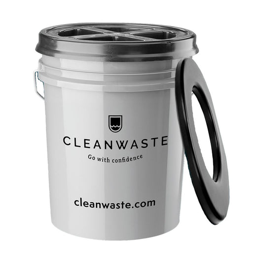 A white plastic Restop Commode portable toilet by NRS, perfect for backcountry use, features a black seat lid leaning against it and the brand's website printed underneath.