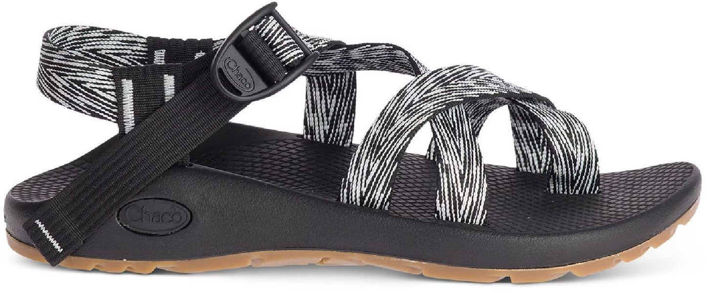 The Chaco Z2 Classic - Women's is a black outdoor sandal with adjustable black and white patterned straps and a tan rubber sole, shown from the side—ideal for hiking or everyday comfort.