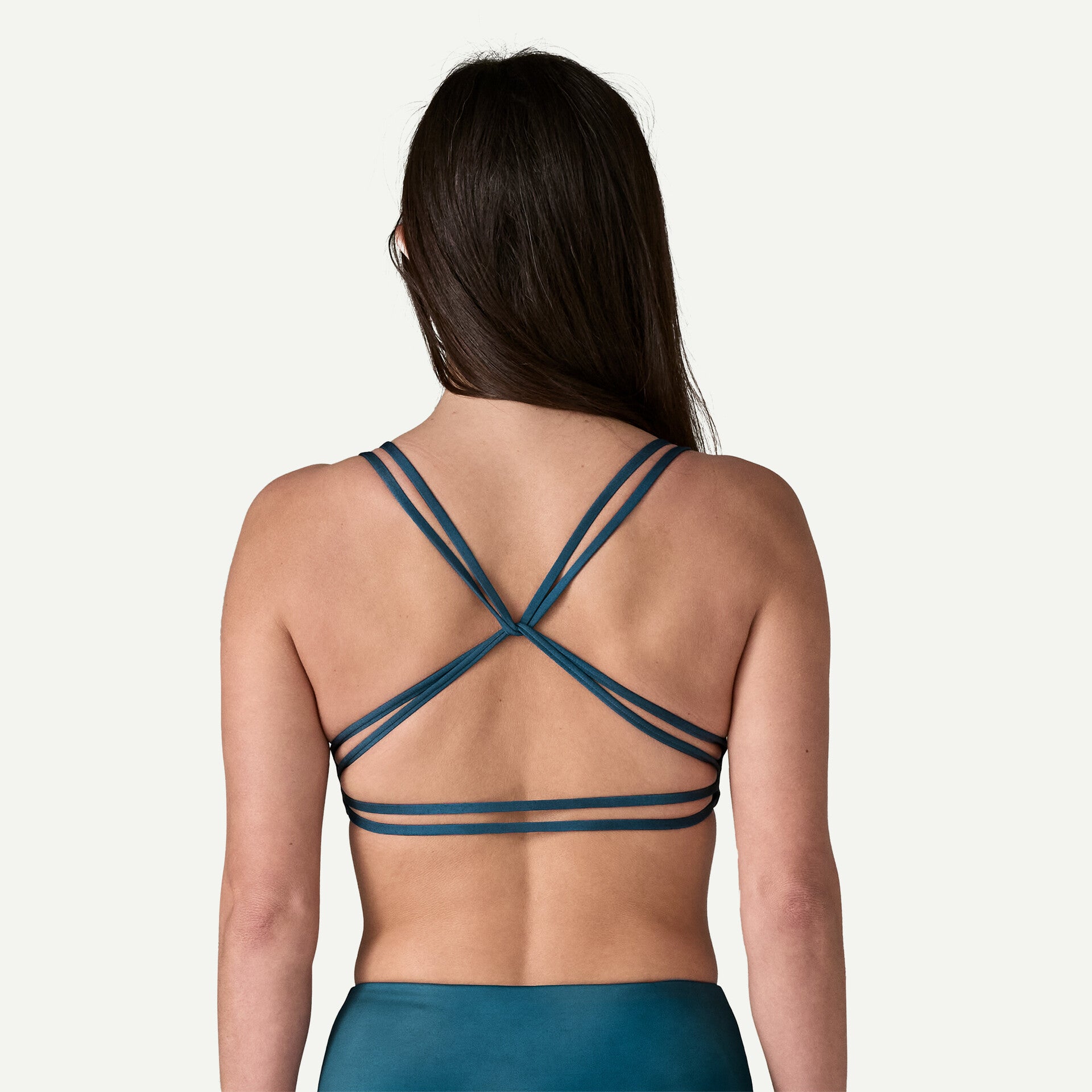 Back view of a person with long hair wearing the teal Reversible Seaglass Bay Top by Patagonia, standing against a plain background.