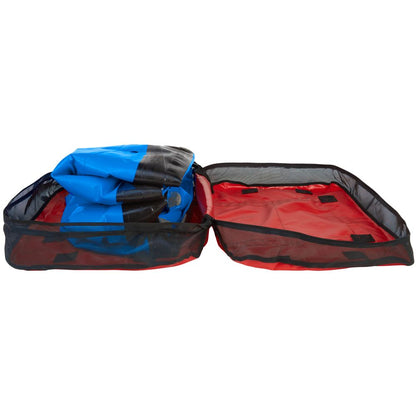 A partially packed blue inflatable kayak snugly fits into an NRS Boat Bag in red and black.