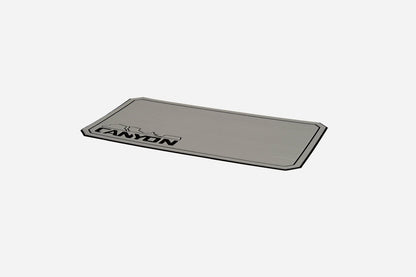 A rectangular metallic badge with "CANYON" and a mountain outline in black on white, ideal for adding style to your Canyon Coolers Cooler Traction Pads or any durable EVA foam cooler traction pad.