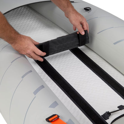 A user secures a black padded seat to the interior floor of the NRS Akamai 110 Inflatable Kayak with Velcro strips.