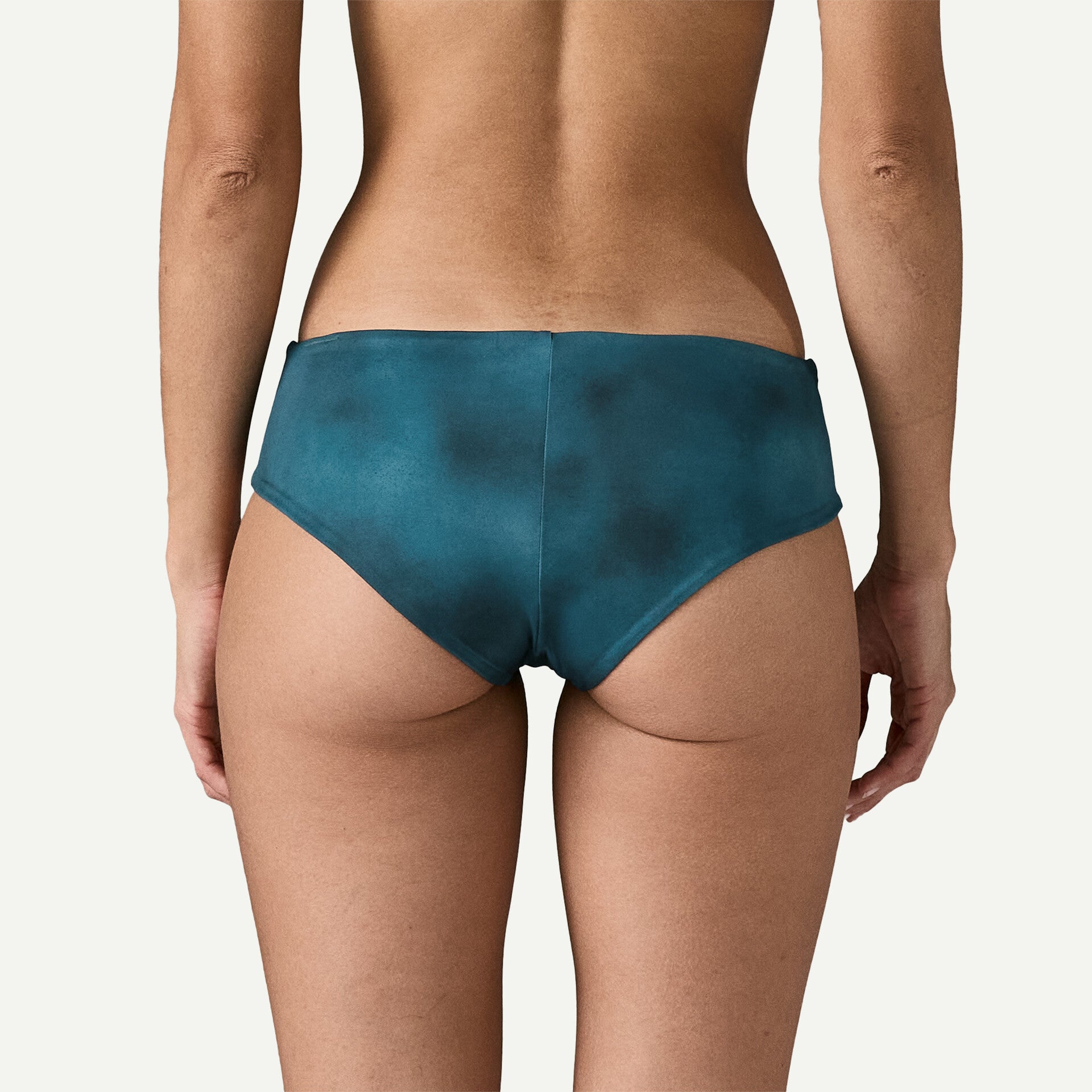 A person is standing with their back to the camera wearing Patagonia's Cheeky Bottom in teal against a plain background.