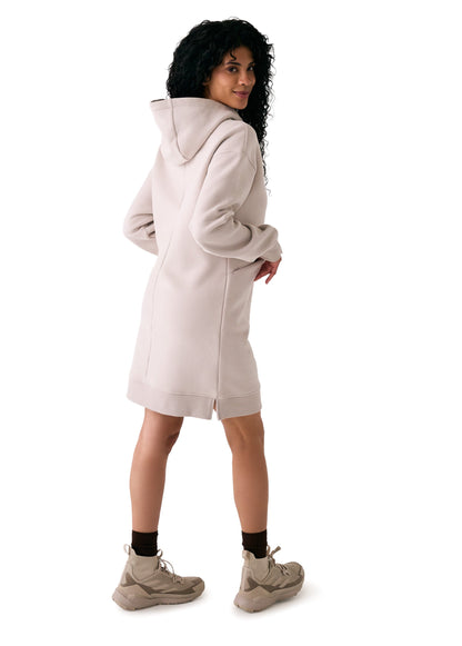 A woman faces away against a white background, wearing the Lole Yonder Hoodie Dress in light beige with beige sneakers and brown socks.