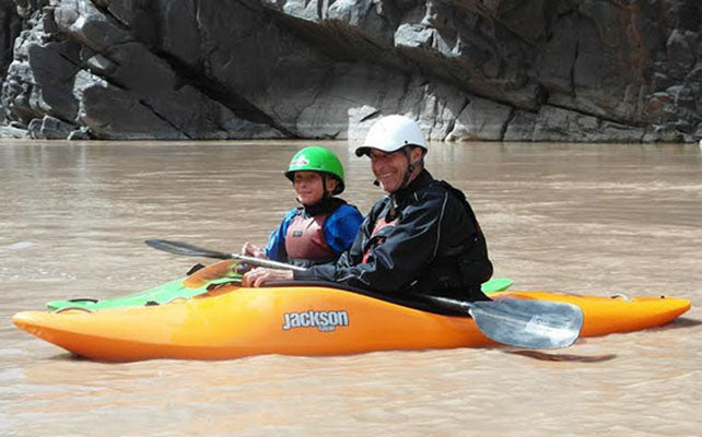 a man and a child in a kayak on a river.