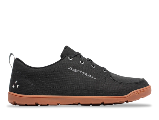 The Astral Loyak All Weather is a black low-top sneaker with a brown rubber sole, lace-up front, and "ASTRAL" branding, made from recycled polyester canvas for minimal ground feel. Shown on a plain white background.