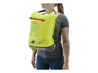 A person stands against a white background wearing an Astral inflatable life vest in bright yellow, with instructions printed on the front, paired with an AirBelt 2.0 Inflatable PFD waist belt flotation device.