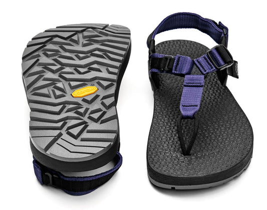 A pair of Bedrock Carin Evo 3D Pro sandals in black and purple—one highlights the Vibram Megagrip sole, while the other displays the secure top strapping and contoured footbed.