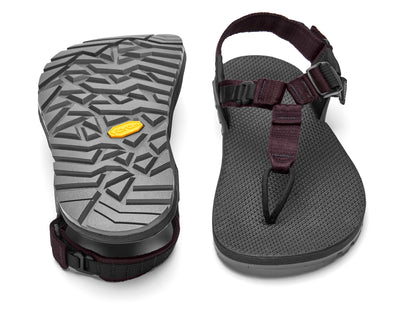 The Bedrock Carin 3D Pro II is a pair of black hiking sandals with adjustable straps and a secure fit; one sandal is shown from above, while the other displays its Vibram Megagrip outsole’s textured tread.