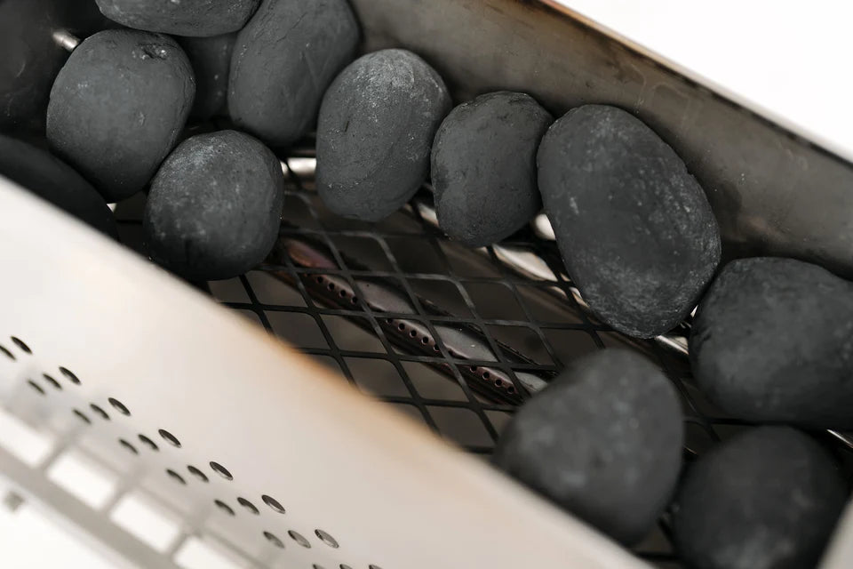 A VolCanNo Trident Combo charcoal grill filled with black rocks, perfect for campfire bans. Manufactured by LavaBox.