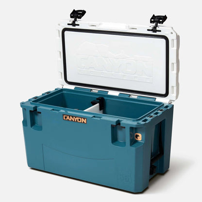 The blue PRO Series Coolers from Canyon Coolers offer a maximum ice-retention design, featuring an open lid, white interior, and built-in divider.
