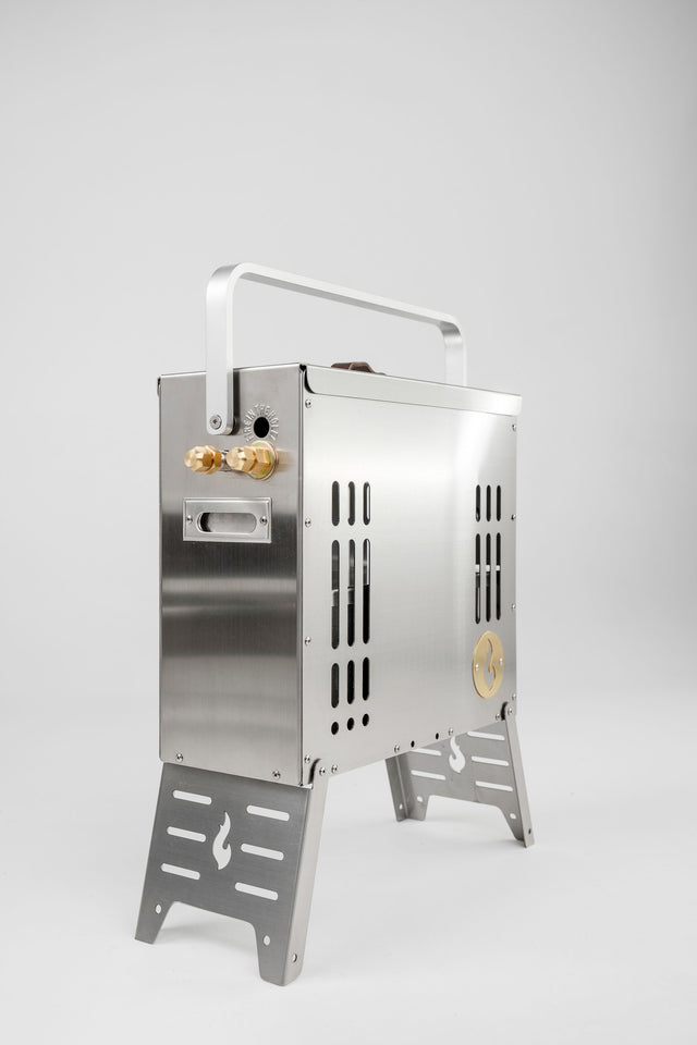 The LavaBox BoomBox Portable Campfire is a compact stainless steel grill with side knobs, vent slits, and a top handle—ideal for smokeless outdoor adventures—shown on a plain white background.