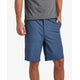 A person is standing against a plain background, casually wearing a gray t-shirt and REEF's Dante Short, which features a 20-inch outseam in blue made from a cotton/poly/spandex blend, with one hand in their pocket.