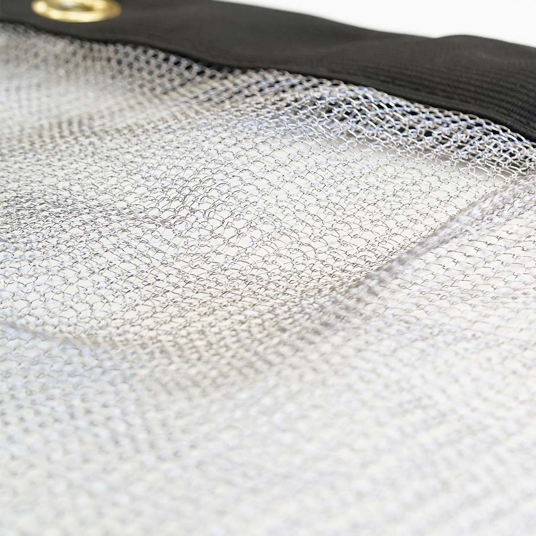 Close-up of the Canyon Coolers Stainless Mesh Drag Bag featuring a stainless steel mesh sheet with a black reinforced edge and brass grommet, designed for outdoor adventures.