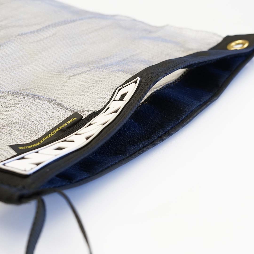 Close-up of Canyon Coolers' Stainless Mesh Drag Bag in gray with a black zipper slightly open, showing a label inside. Ideal for outdoor adventures, it includes a grommet at the top right corner.