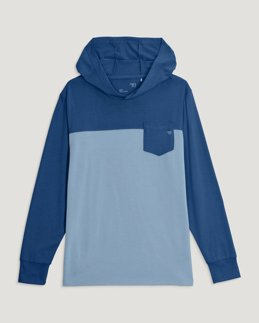 The Free Fly Youth Colorblock Shade Hoodie is a kids' long-sleeve, two-tone blue hoodie with a front chest pocket and UPF 50+ protection, shown laid flat on a light background.