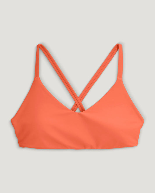 The Free Fly Wavebound Cross-tie Bikini Top in orange features thin crisscross back straps and soft TideKnit fabric, shown on a plain light background.