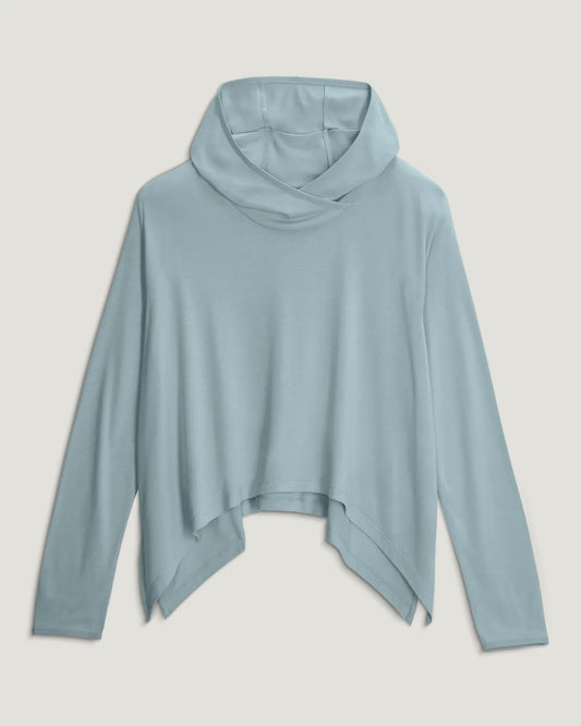 The Free Fly Women's Bamboo Lightweight Cropped Hoodie in light blue features long sleeves, an asymmetrical hem, a draped cowl neck, and UPF 20+ sun protection, shown laid flat on a neutral background.