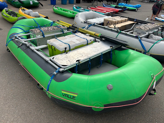 A fleet of Valle green rafts in a parking lot available for rental.