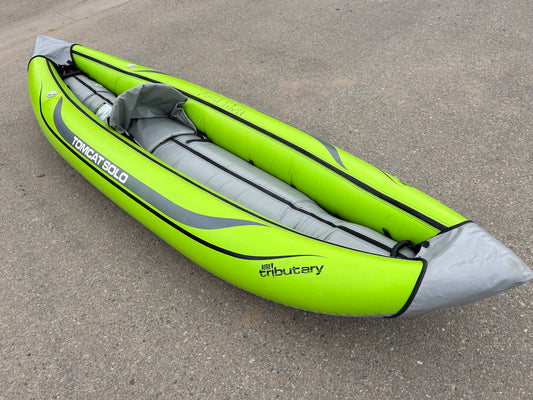 An AIRE Demo Tomcat Solo inflatable kayak on pavement.