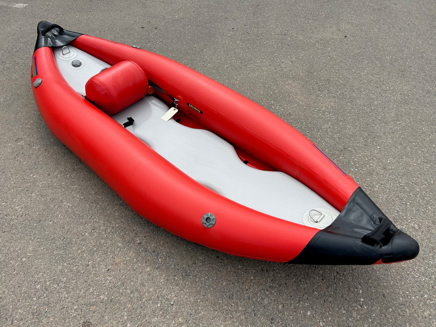 An Valle Truckee Ducky Solo inflatable kayak in red and black color, with a drop stitch floor, resting on the ground.