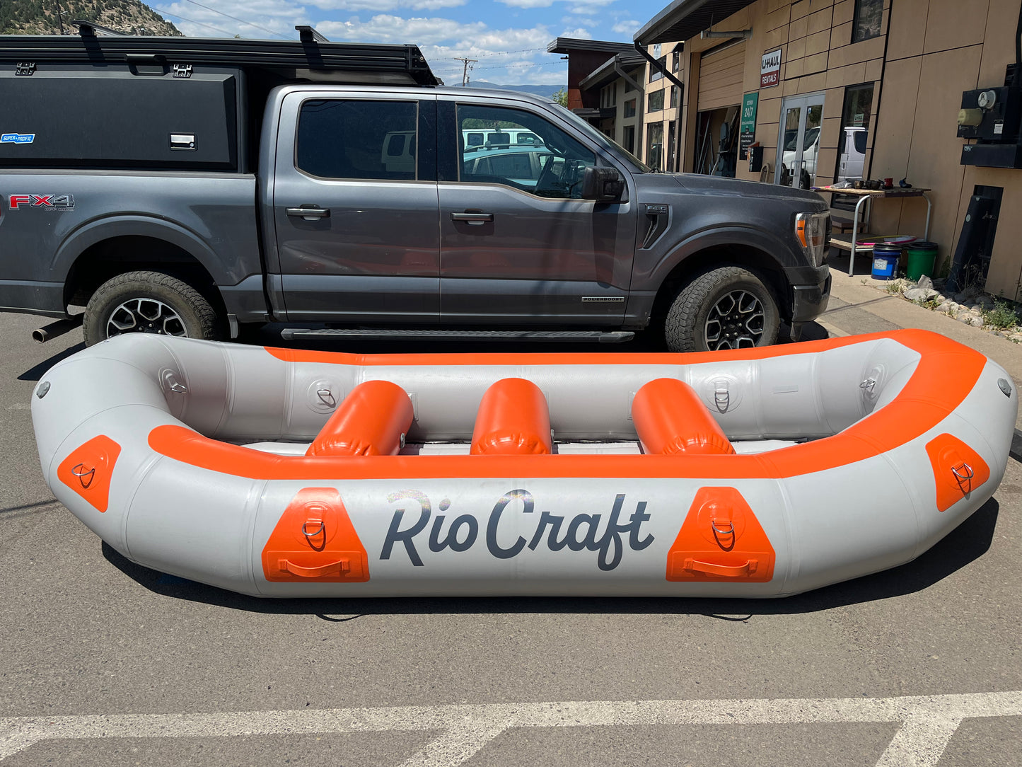 The Consignment 13' Colorado raft from Rio Craft is parked in front of a truck.