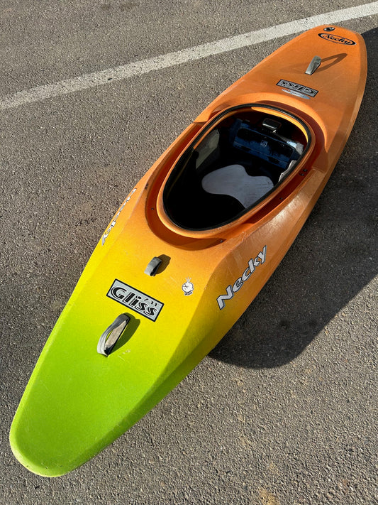 A well-loved Jackson Kayak Consignment Necky Gliss, yellow and orange, parked in a parking lot.