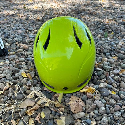 The Demo Wanderer helmet by Sweet Protection, made from carbon fiber reinforced polymer, is placed on a surface of small rocks and dried leaves.