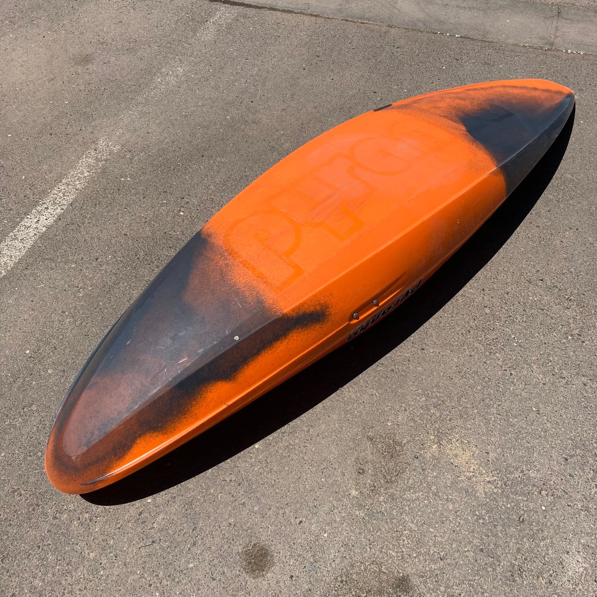 A Consignment Ripper 2 | Small surfboard by 4Corners Riversports laying on the ground in a parking lot.