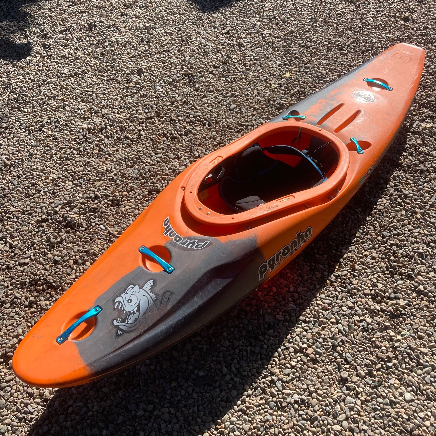 An orange and black Demo Ripper 2.0 SM kayak laying on the ground. Brand: Pyranha