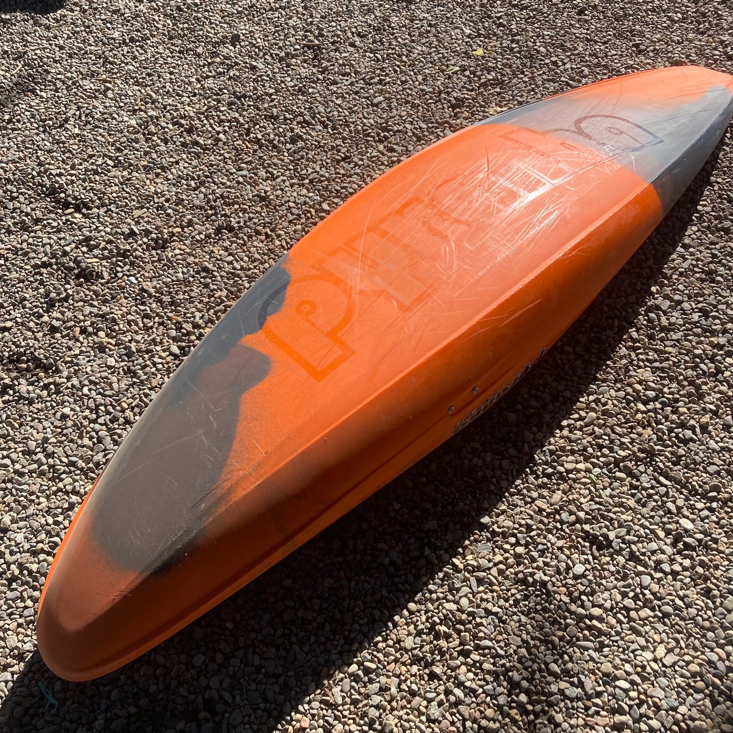 An orange and black Pyranha Demo Ripper 2.0 LG paddle board laying on the ground.