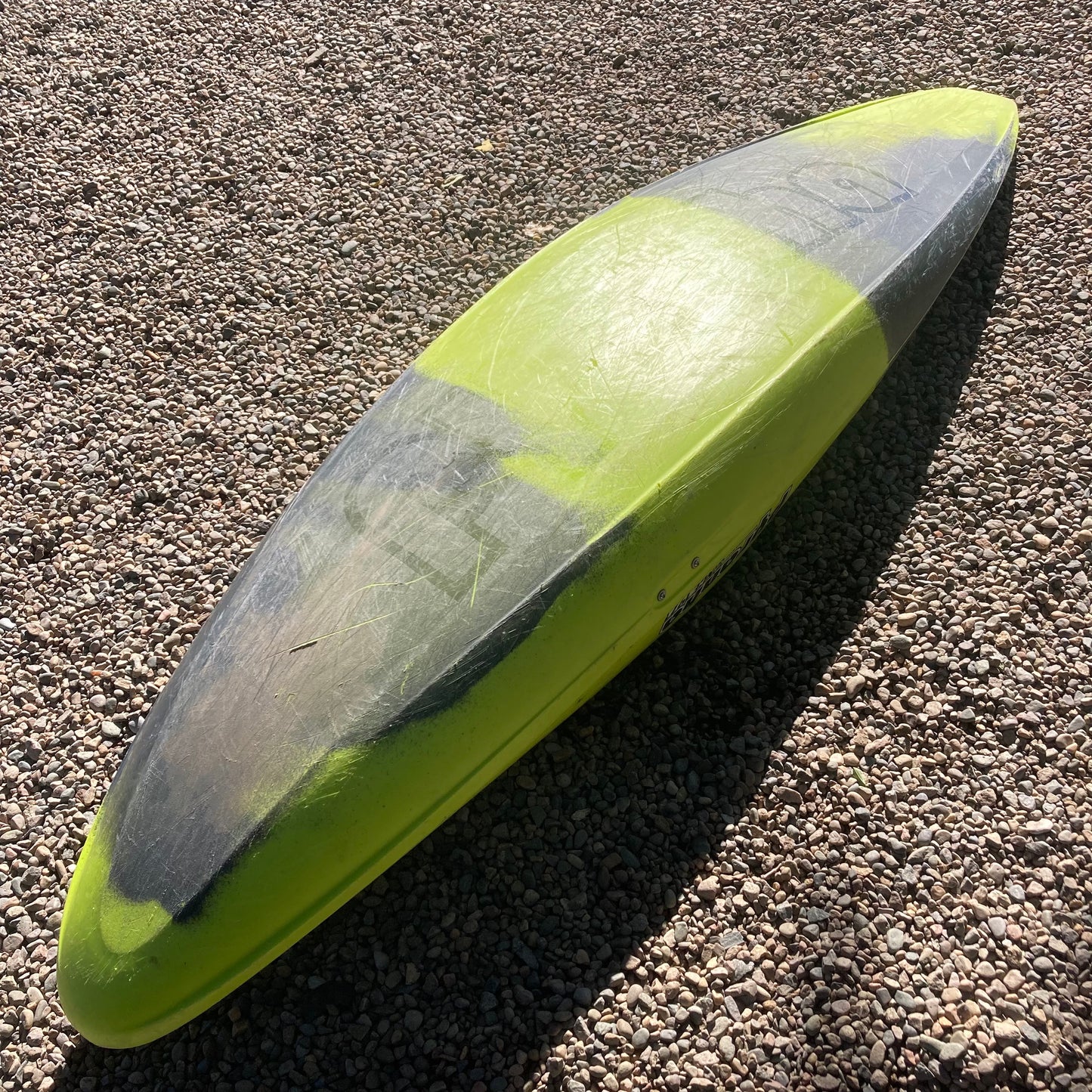 A yellow and black Demo Ripper 2.0 MD surfboard laying on the ground, made by Pyranha.