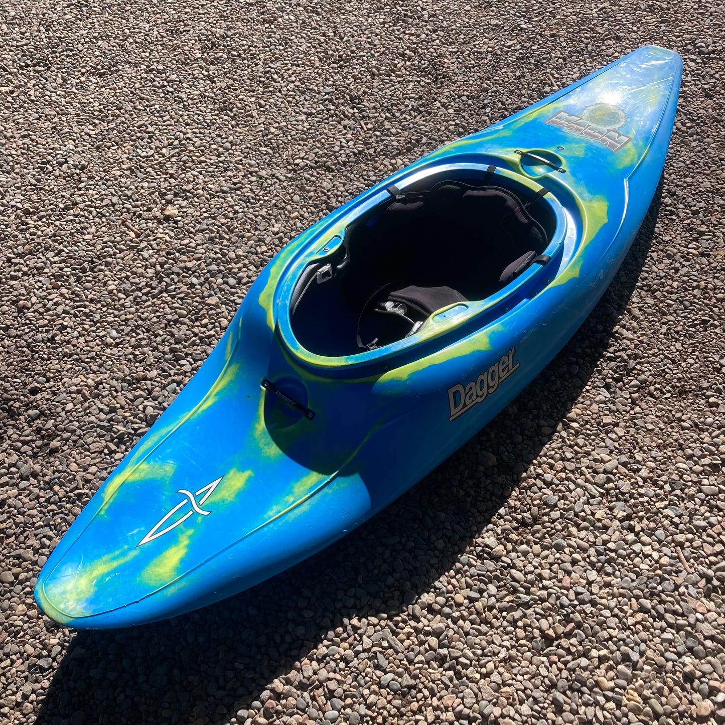 A blue and yellow Demo Supernova kayak laying on the ground. (Dagger)